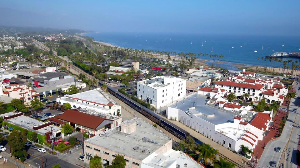A photo of the Pacific Surfliner traveling through the middle of Santa Barbara in a wide drone shot of the city and the beach.
Credit: pacificsurfliner.com